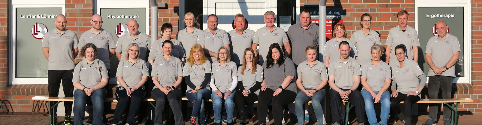 Ein Teamfoto vor der Praxis mit 10 Männern und 14 Frauen.