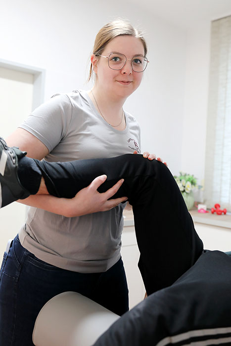 Eine Frau hält das angewinkelte Bein eines Patienten.